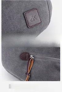 Detailed macro view of embossed leather logo and premium zipper pull on grey canvas tote bag