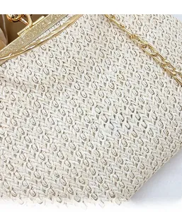 Close-up of woven straw texture with floral embossed gold clasp and metal chain strap