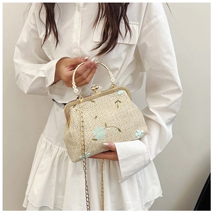 Détail du sac tressé vintage avec broderie florale et poignée en perles porté par un mannequin