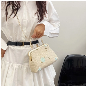 Détail du sac à main en paille beige avec broderies florales bleues et chaîne dorée