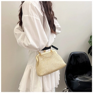 Detail view of woven straw shell bag with golden twist lock and thin chain strap