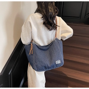Detailed view of a large capacity washed denim tote bag carried by a model on stairs.
