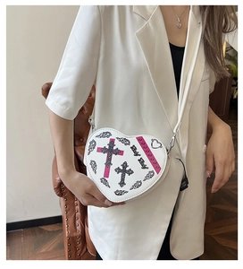 Détail du sac à bandoulière blanc en forme de cœur avec motif de croix et lanière