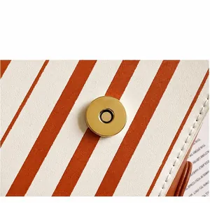 Close-up of the light gold magnetic buckle and white stitching on the striped piano bag
