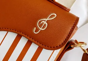 Detail of a brown leather bag with embroidered golden treble clef and striped pattern