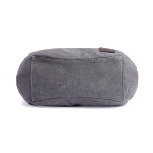 Bottom view of dark grey canvas tote bag with reinforced stitching and brown leather logo tag