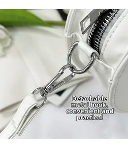 Gros plan du crochet métallique argenté et de la bandoulière amovible du sac blanc