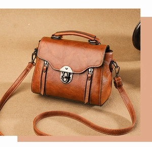 Detail shot of the brown vintage crossbody bag with metal buckle and glossy texture
