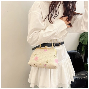 Détails d'un sac à main beige tissé avec broderie florale rose et fermoir en métal doré