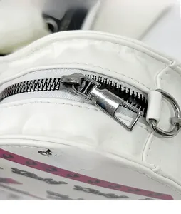 Gros plan sur la fermeture éclair argentée et le motif cœur sur le sac en similicuir blanc