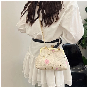 Détails de broderie florale sur un sac en paille beige avec fermoir doré rétro