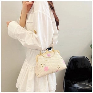 Dettaglio borsa intrecciata crema con ricamo floreale rosa e catena dorata elegante