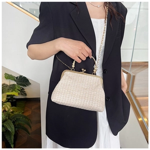 Detail of a minimalist beige straw woven bag with gold metal handle and chain strap