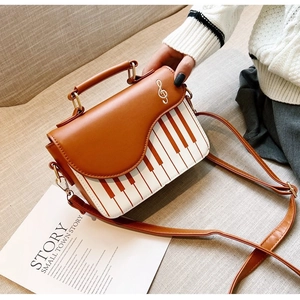 Detail view of piano key pattern purse with brown flap and treble clef metal buckle