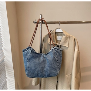 Detail view of washed blue denim tote bag with brown woven rope handle and retro texture