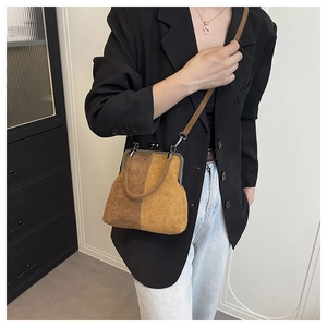 Close-up of vintage shell-style crossbody bag with metal frame clasp and suede texture