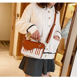 Close-up of piano key pattern crossbody bag with golden clef symbol and brown PU flap