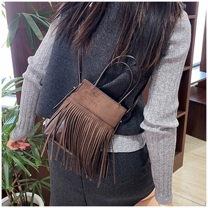 Detail of bohemian dark brown suede fringe bag with adjustable shoulder strap and handle