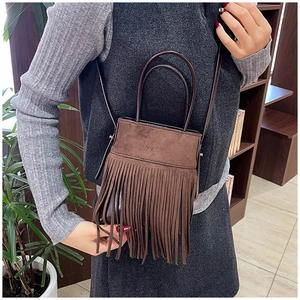 Close-up of a brown matte fringe handbag with tassels and top handles for a retro style