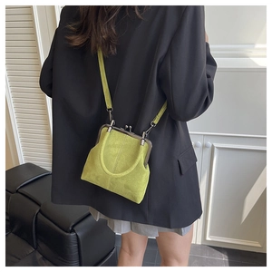 Green retro kiss-lock shell bag with a slim leather strap worn by a model in a modern style