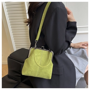 Détail d'un sac rétro vert citron avec fermoir métallique porté sur un tailleur noir chic
