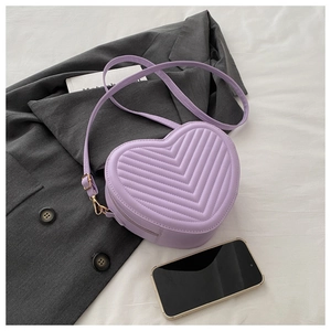 Vue détaillée du sac matelassé en forme de cœur lilas sur un blazer gris chic