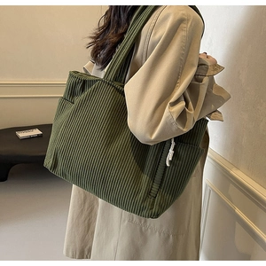 Dettaglio della borsa tote in velluto a coste verde scuro con tasca laterale e tracolla larga