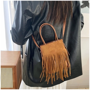 Close-up of a brown tassel bucket bag with bohemian fringe detail on a model