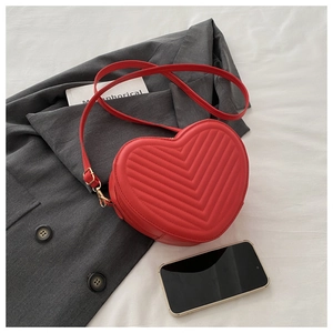 Détail du sac rouge en forme de cœur avec cuir matelassé en V et boucles dorées