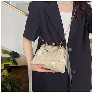 Dettaglio borsa ricamata beige con chiusura in metallo dorato vintage e tracolla a catena