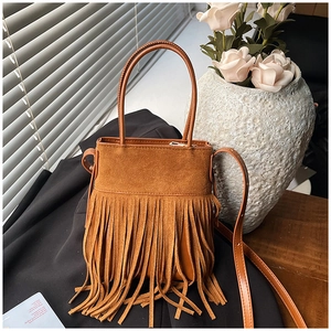 Detail of brown suede bucket bag featuring cascading tassels and adjustable shoulder strap