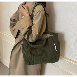 Dettaglio della borsa tote in velluto a coste verde scuro con strisce verticali e nodi laterali
