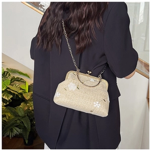 Dettaglio di una pochette vintage in paglia con ricamo floreale e catena dorata