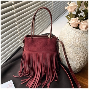 Close-up of burgundy fringe bucket bag with suede texture and boho tassels