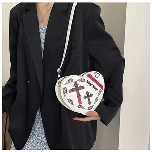 Vue détaillée d'un sac bandoulière blanc en forme de cœur avec des motifs de croix imprimés