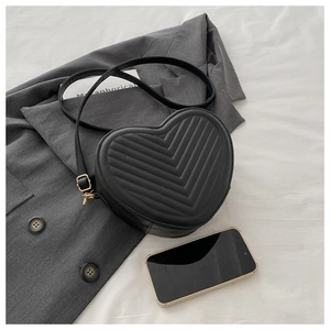 Détail du sac bandoulière noir en forme de cœur avec matelassage chevron et zip doré