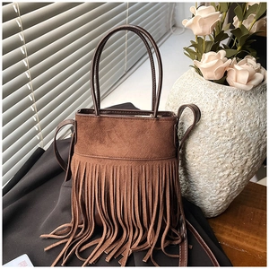 Detail of brown suede bucket bag featuring long fringe tassels and a bohemian vintage style
