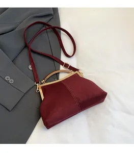 Détail du sac coquille en daim bordeaux avec fermoir en métal doré et surpiqûres