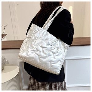 Détail d'un sac cabas matelassé blanc brillant avec une petite étiquette de mode