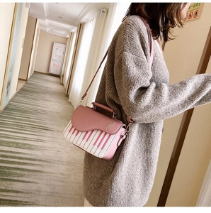 Detail view of pink and white piano key crossbody bag with golden treble clef metal charm