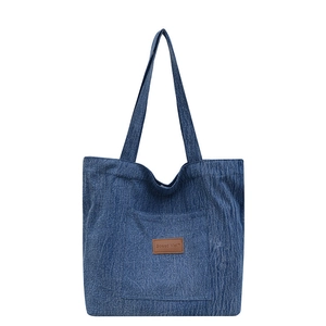 Sac fourre-tout en denim bleu avec étiquette en cuir et longues bretelles sur blanc