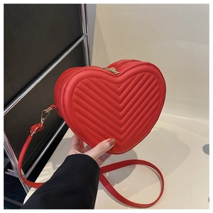 Détail du sac matelassé rouge en forme de cœur avec zip doré et texture en cuir PU fin