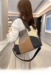 Detail of color-block canvas tote bag featuring brown woven handles and adjustable strap