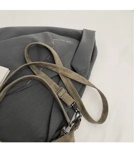 Detail of adjustable khaki shoulder strap with silver metal buckle and rotating hook
