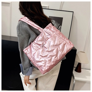 Détail d'un grand sac cabas rose matelassé au fini brillant porté par un mannequin