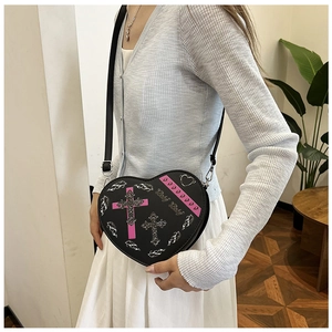 Détail du sac à bandoulière en forme de cœur avec imprimés gothiques et boucle argent