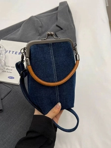 Detail of retro denim crossbody phone bag with white stitching and metal kiss lock