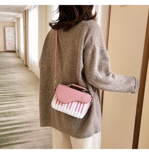 Detail of pink and white piano key crossbody bag with treble clef metal hardware
