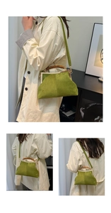 Détail du sac coquille en daim vert avec poignée en bois et cadre en métal doré