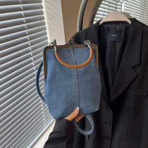 Close-up of denim bucket bag with bronze metal clasp and orange-brown handle details